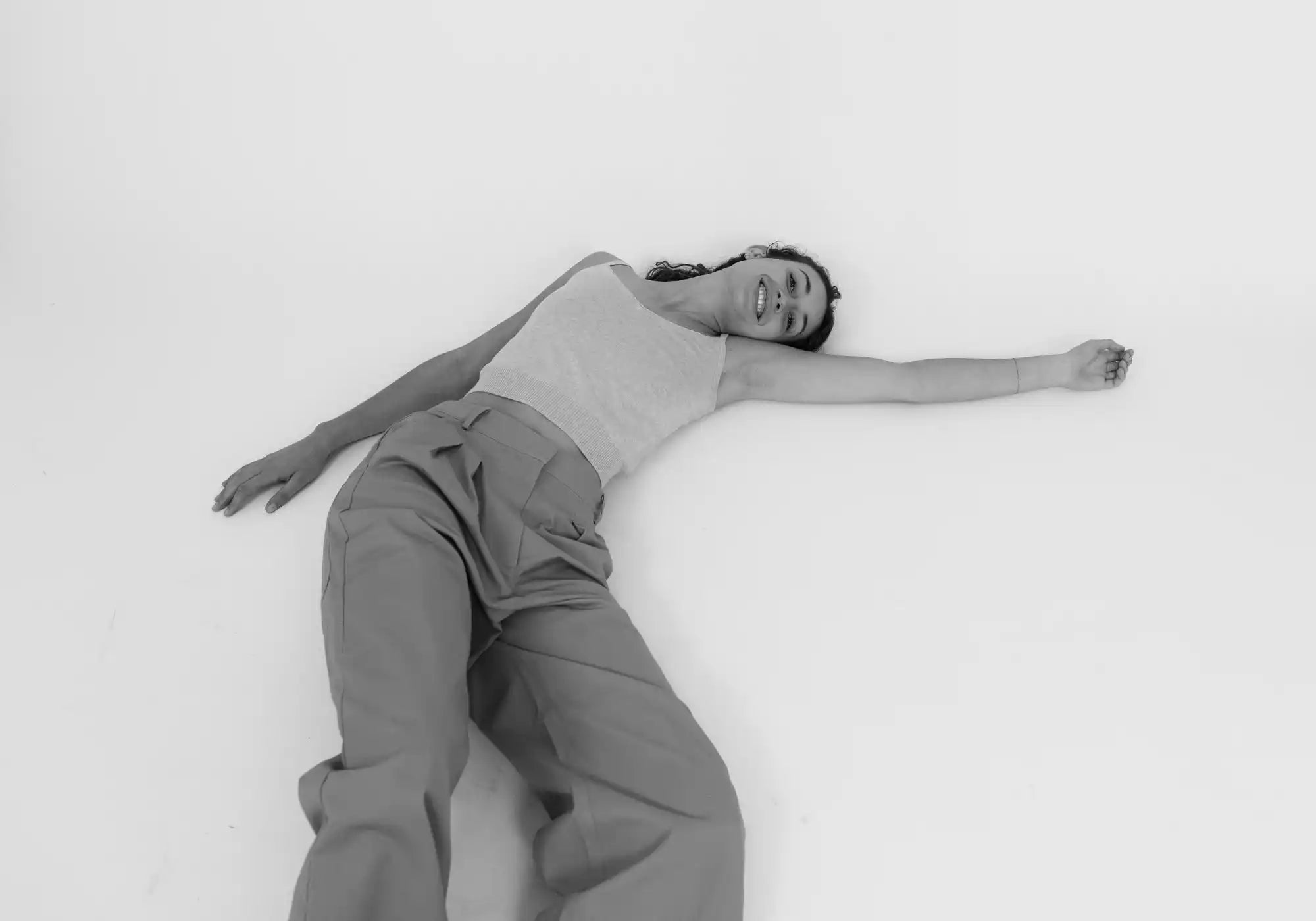Woman wearing a white sleeveless top and trousers lying on the floor