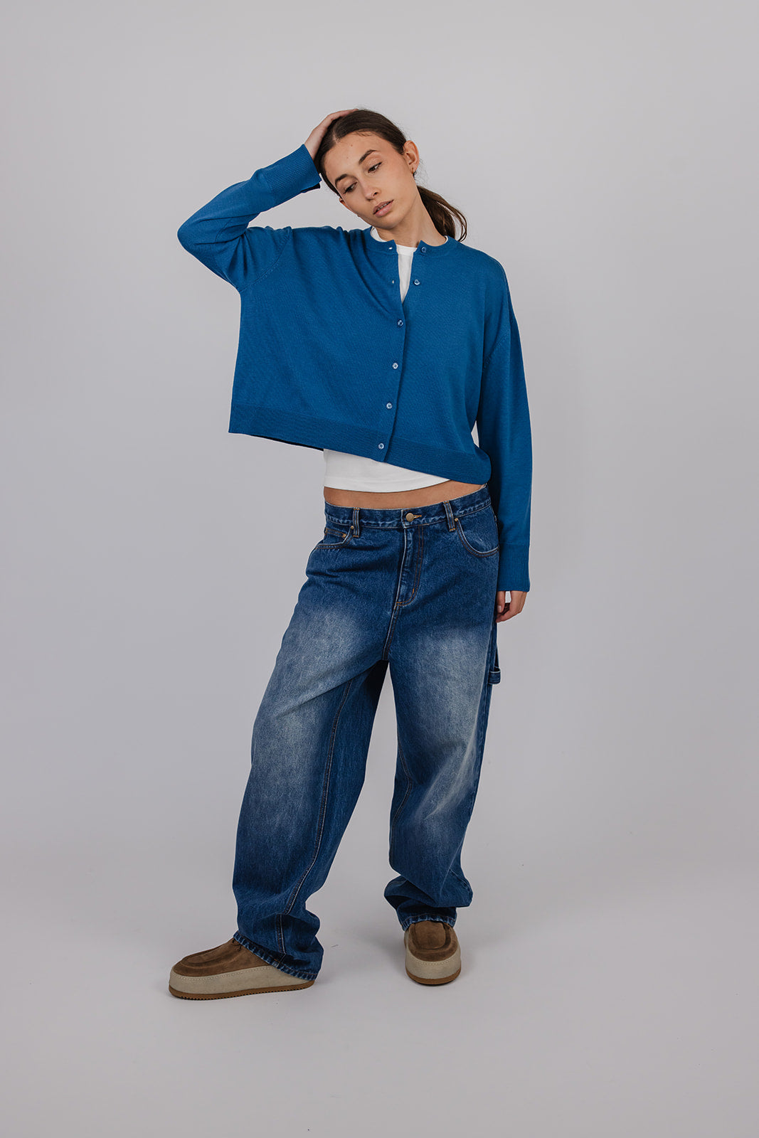 Model wearing a blue merino cardigan and blue carpenter jeans by Vic and Bert.