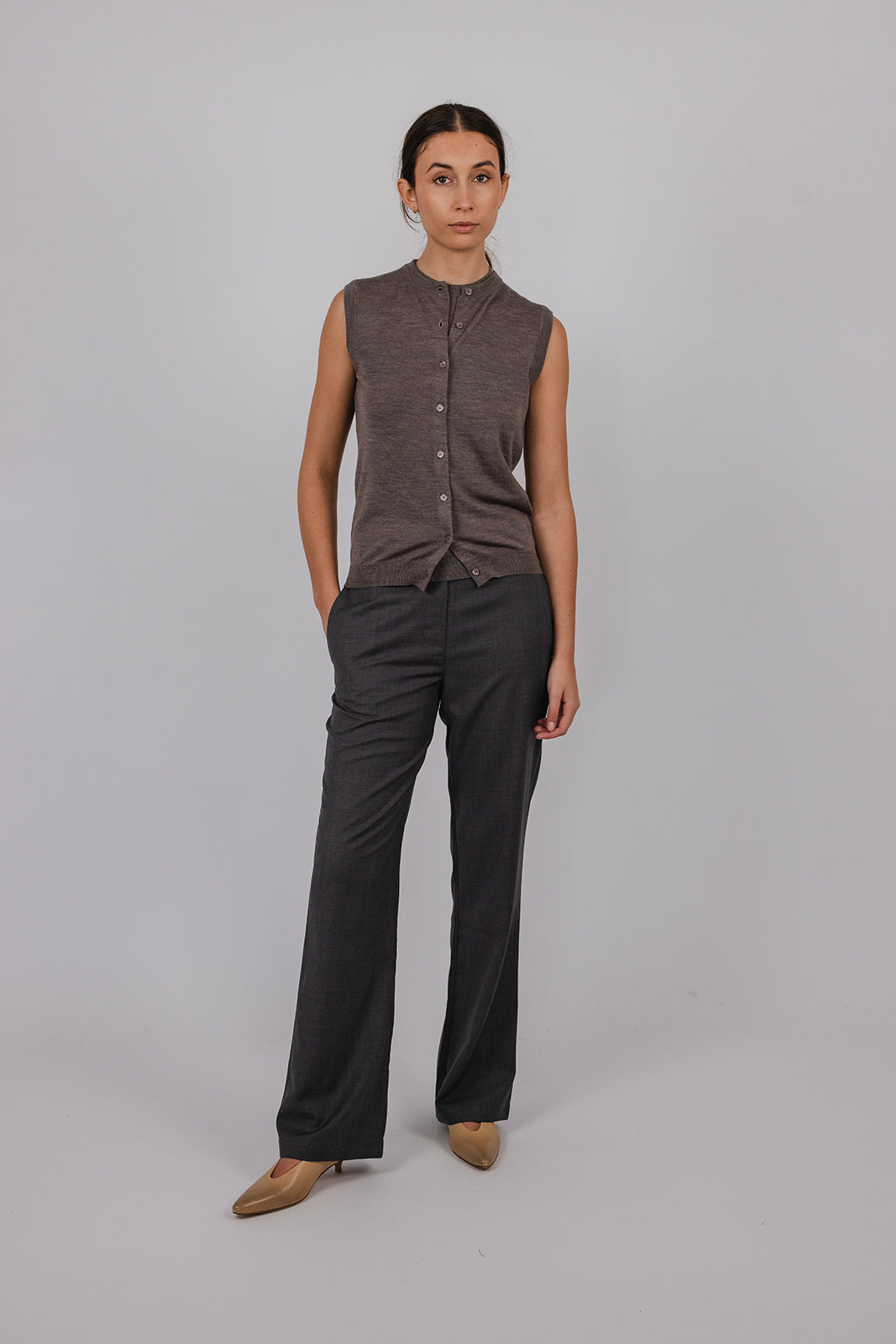 Model wearing a sleeveless merino vest and grey tailored suit pants by Vic and Bert.