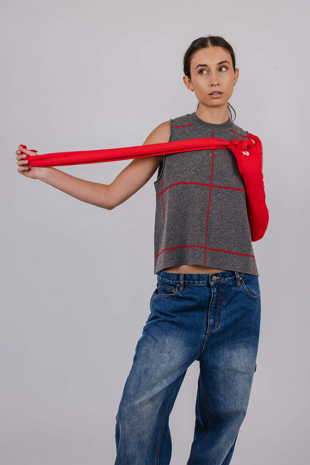 Model wearing a grey and red cashmere vest, blue carpenter jeans, and red cashmere gloves by Vic and Bert.