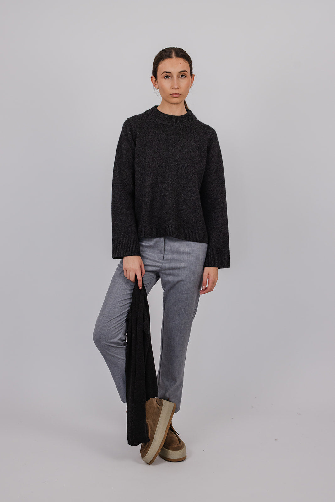 Model wearing a charcoal cashmere a-line knit and grey suit pants by Vic and Bert.