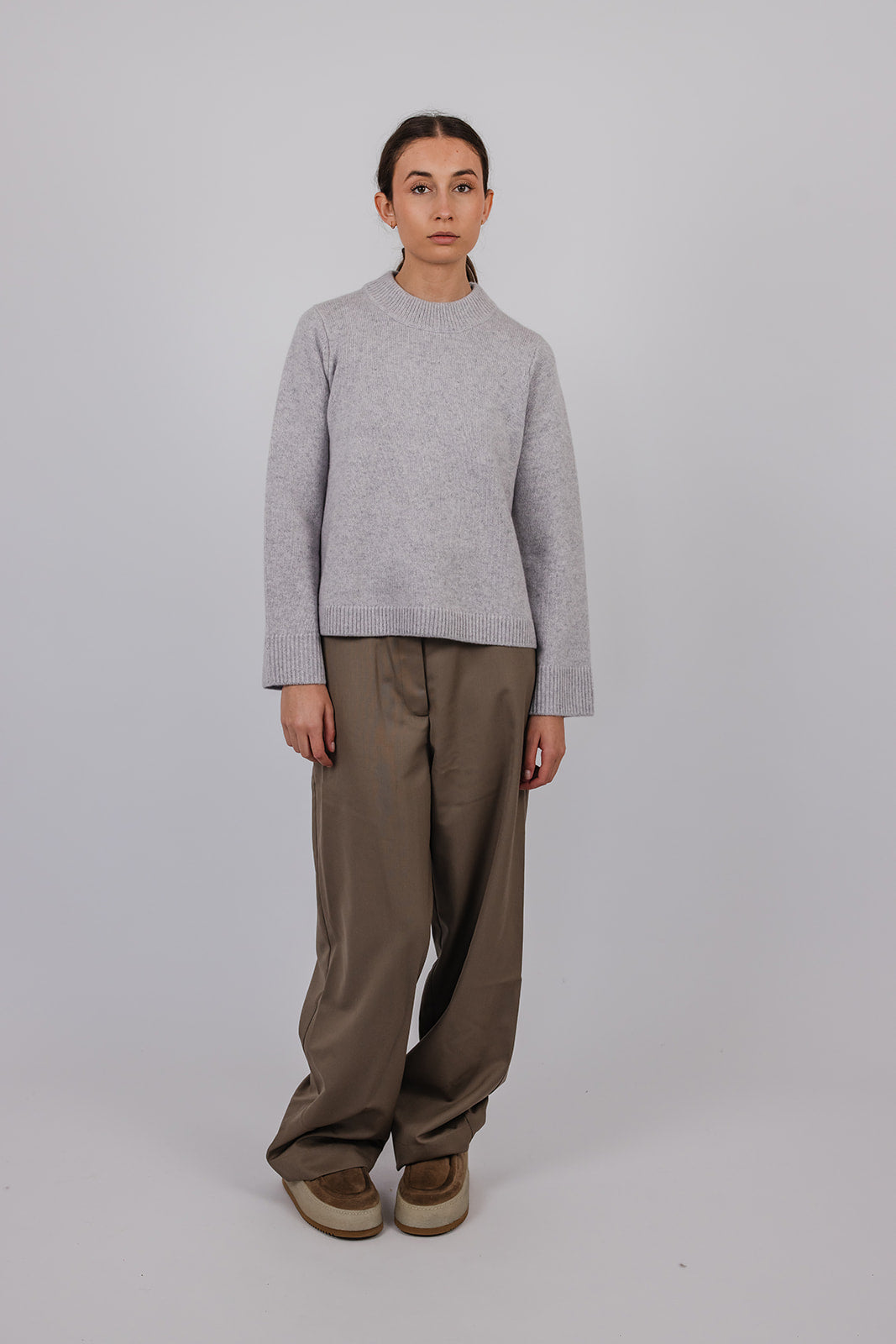 Model wearing a pale grey cashmere a-line knit and taupe suit pants by Vic and Bert.
