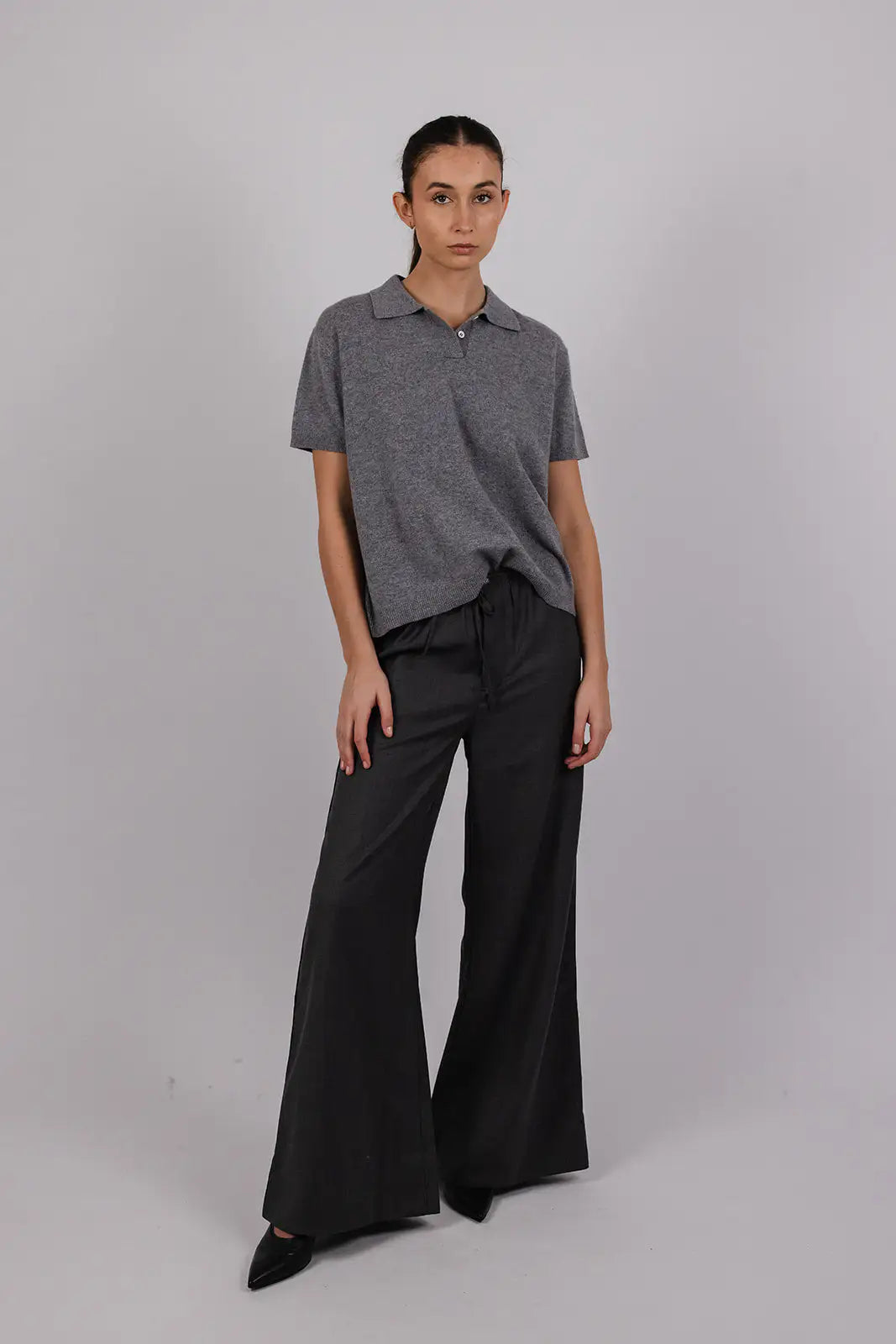 Model wearing a grey cashmere polo by Vic and Bert.