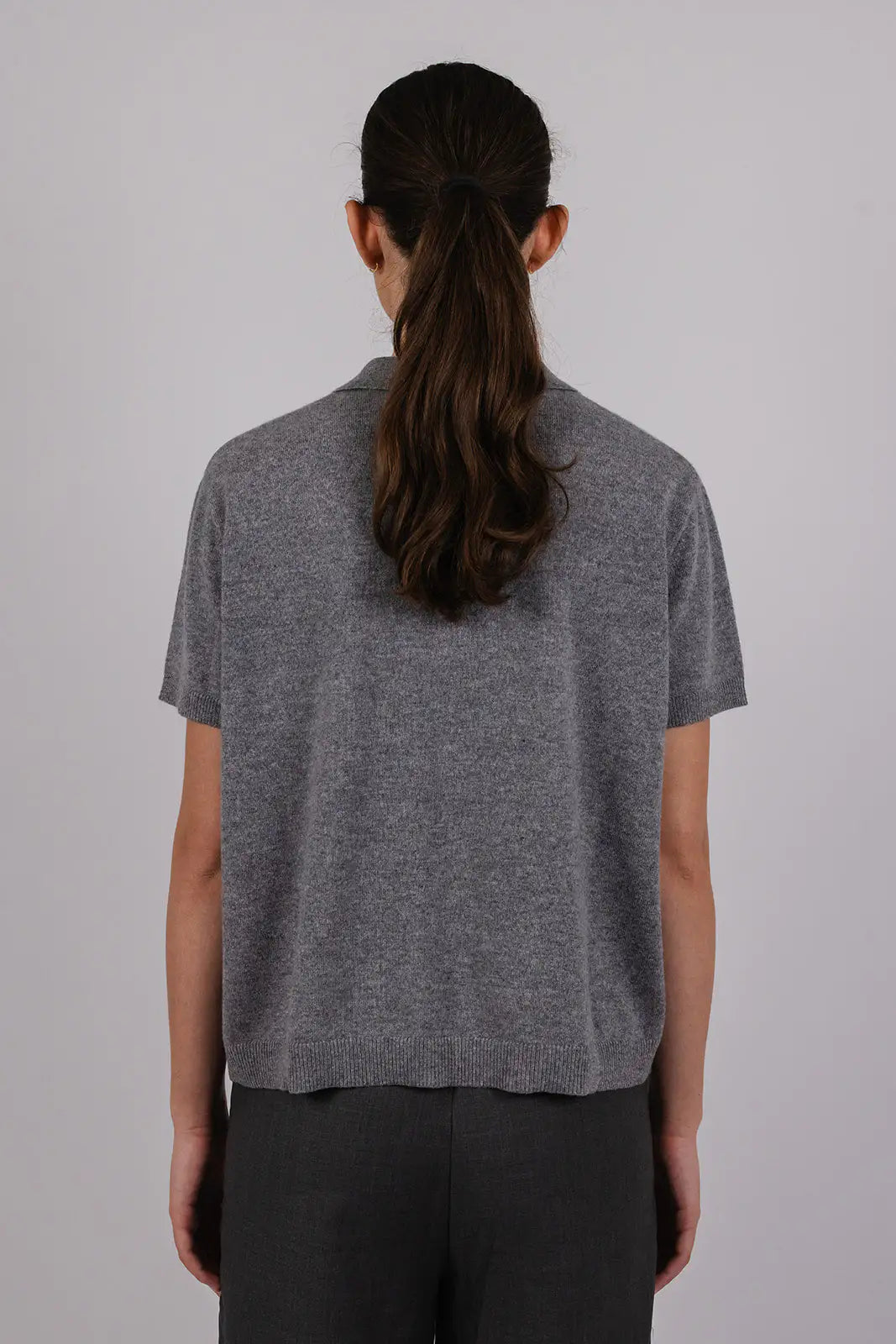 Model wearing a grey cashmere polo by Vic and Bert.