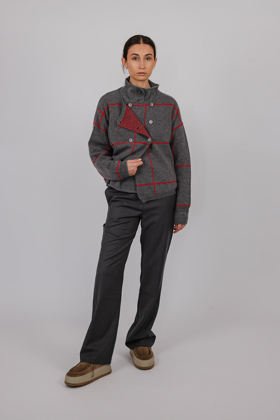 Model wearing a grey and red cashmere double breasted cardigan and grey suit pants by Vic and Bert.