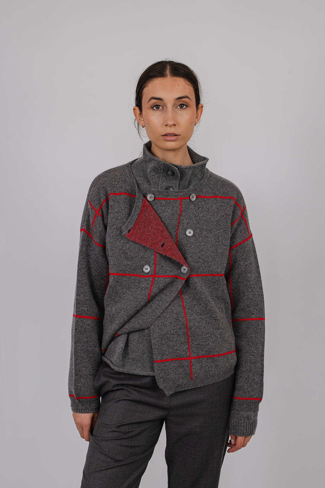 Model wearing a grey and red cashmere double breasted cardigan and grey suit pants by Vic and Bert.