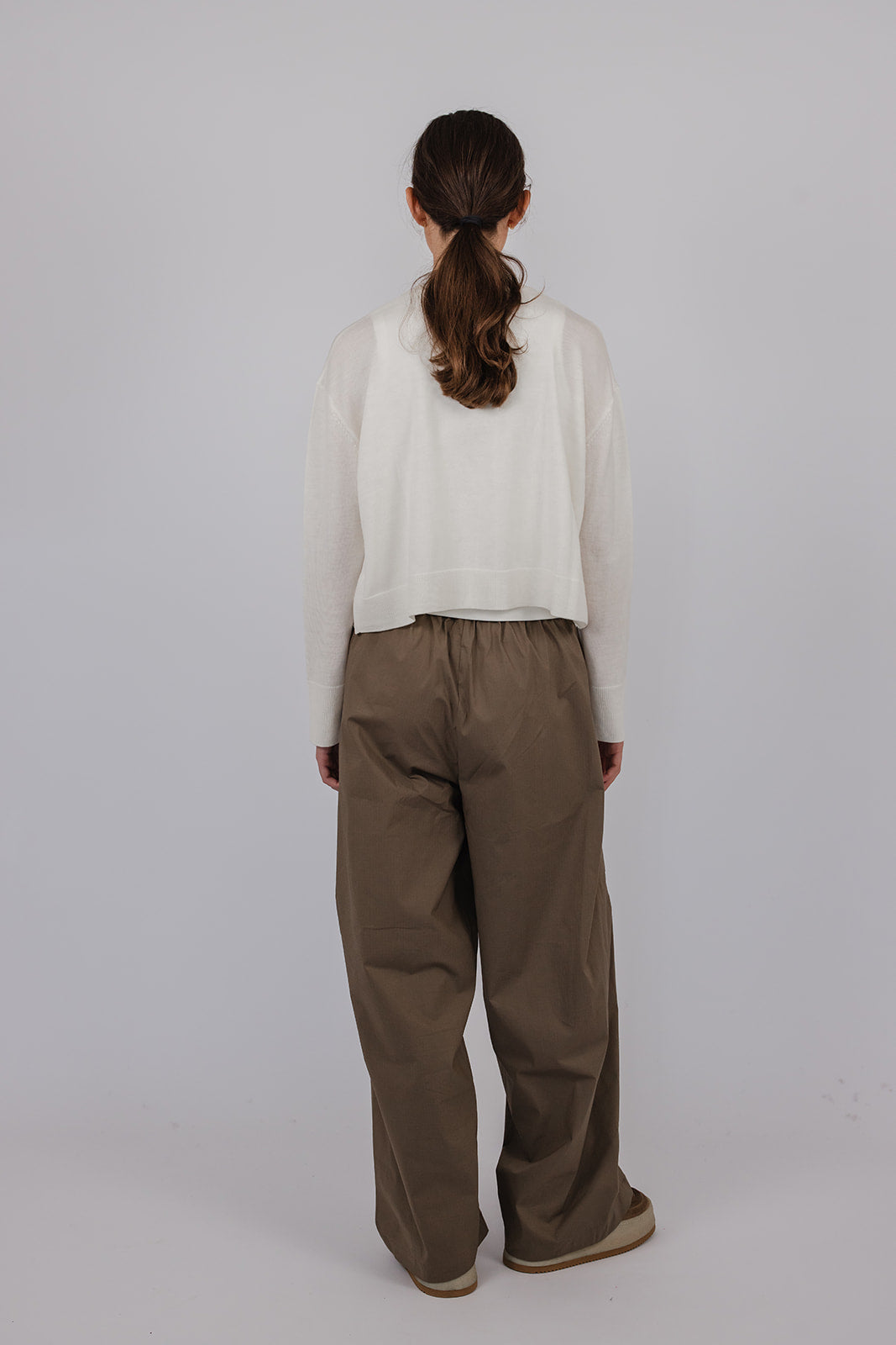 Model wearing a chalk coloured merino cardigan and green pants by Vic and Bert.