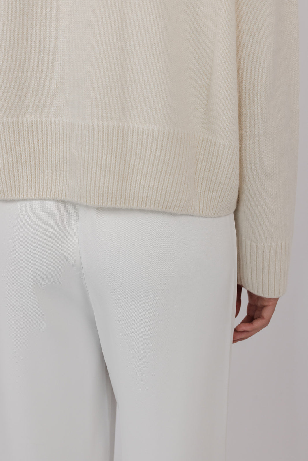 Model wearing a chalk coloured cashmere knit with white pants by Vic and Bert.