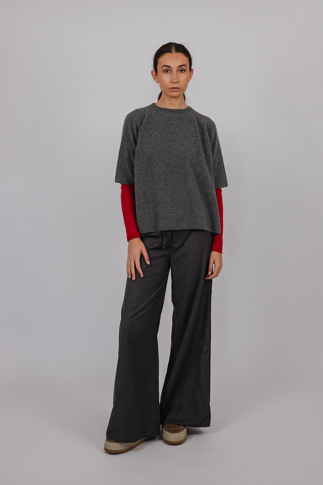 Model wearing a grey cashmere tee over a red long sleeve tee with grey suit pants by Vic and Bert.