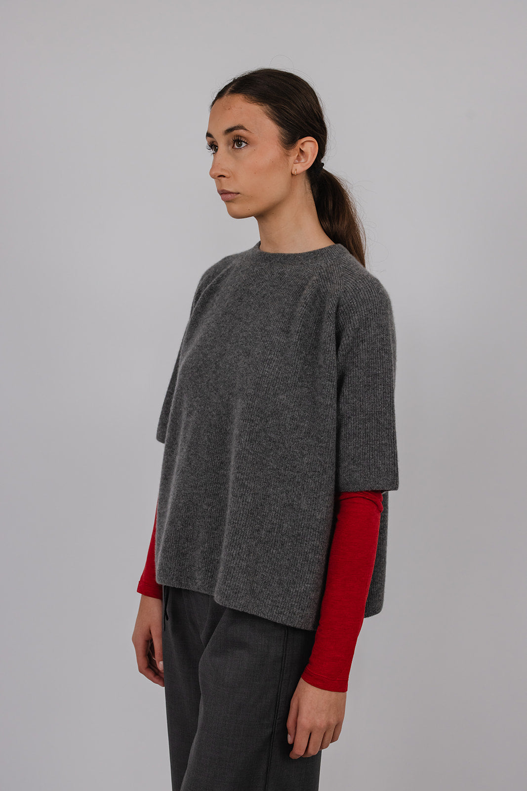 Model wearing a grey cashmere tee over a red long sleeve tee with grey suit pants by Vic and Bert.