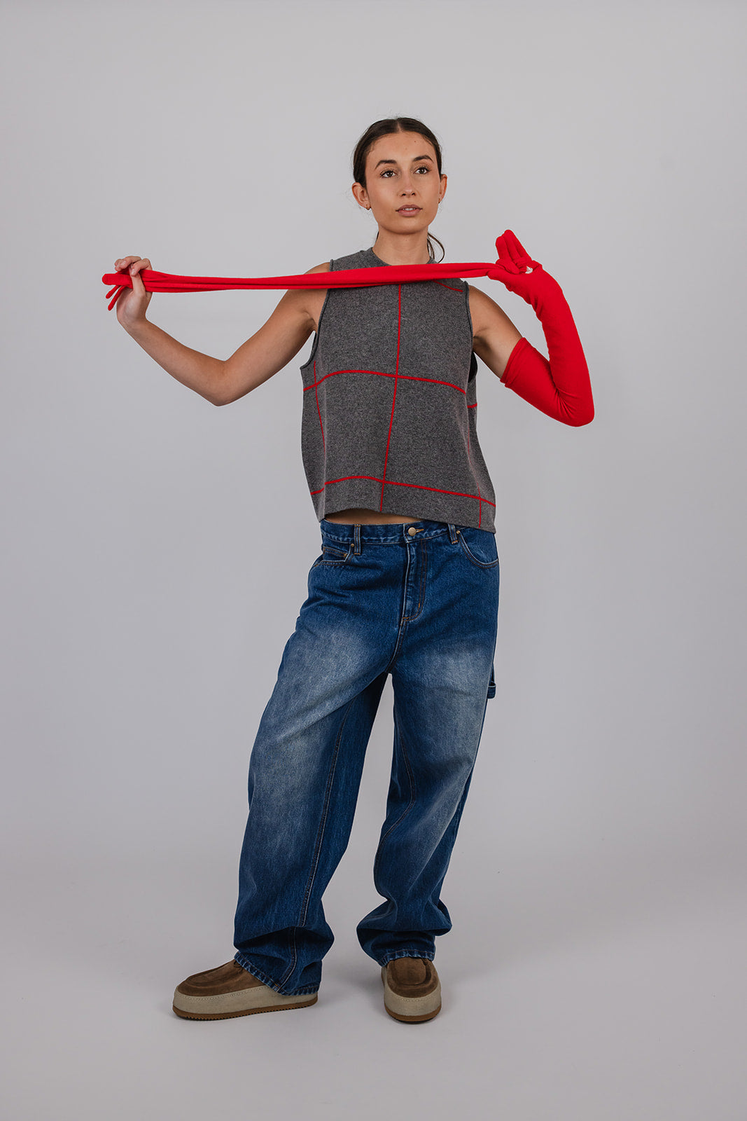 Model wearing a grey and red cashmere vest, blue carpenter jeans, and red cashmere gloves by Vic and Bert.