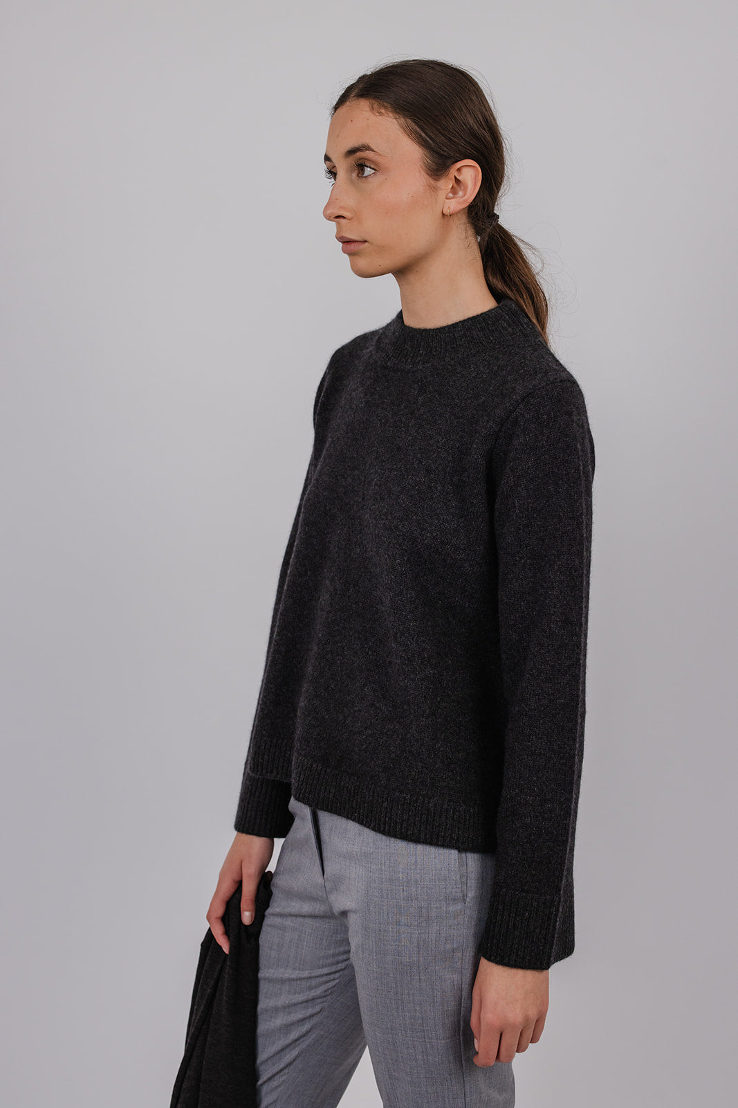 Model wearing a charcoal cashmere a-line knit and grey suit pants by Vic and Bert.