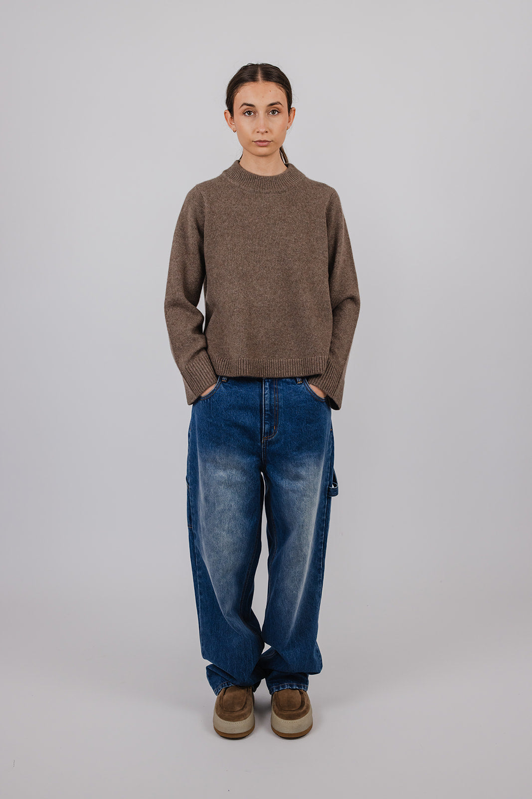 Model wearing a taupe cashmere a-line knit and blue carpenter jeans by Vic and Bert.
