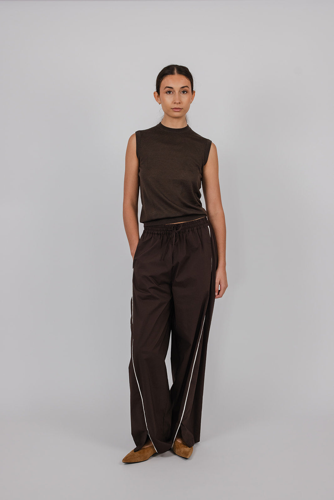 Model wearing a chocolate coloured sleeveless merino vest and pants by Vic and Bert.