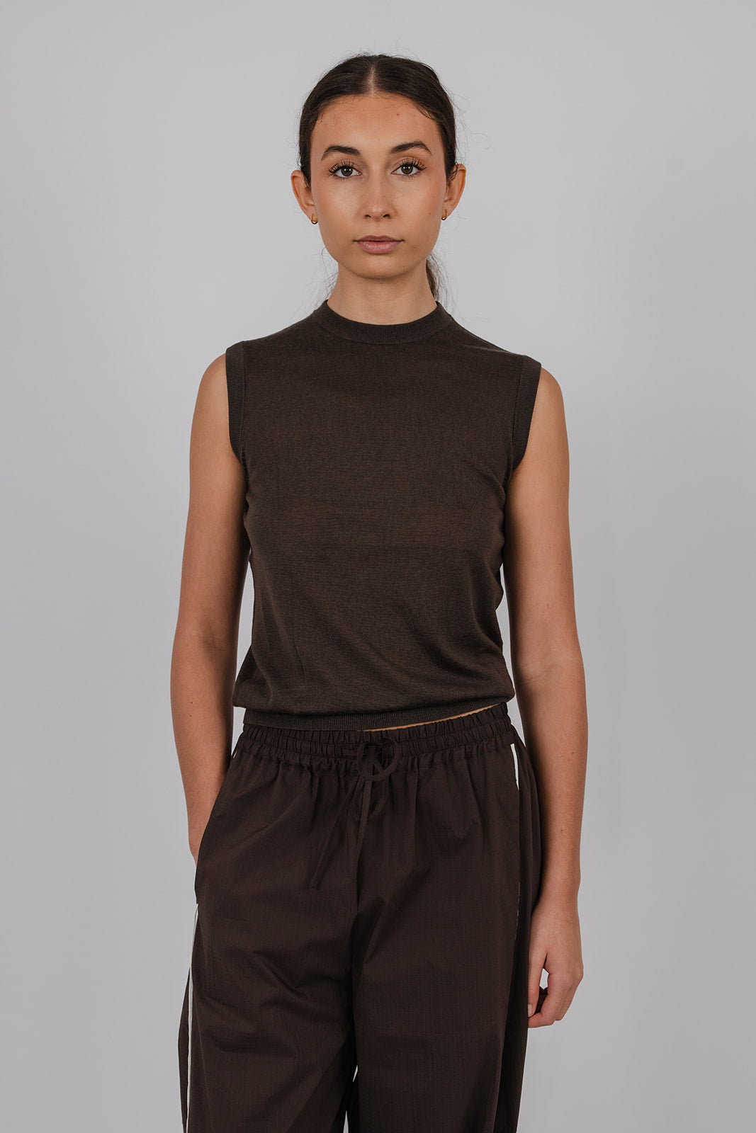 Model wearing a chocolate coloured sleeveless merino vest and pants by Vic and Bert.