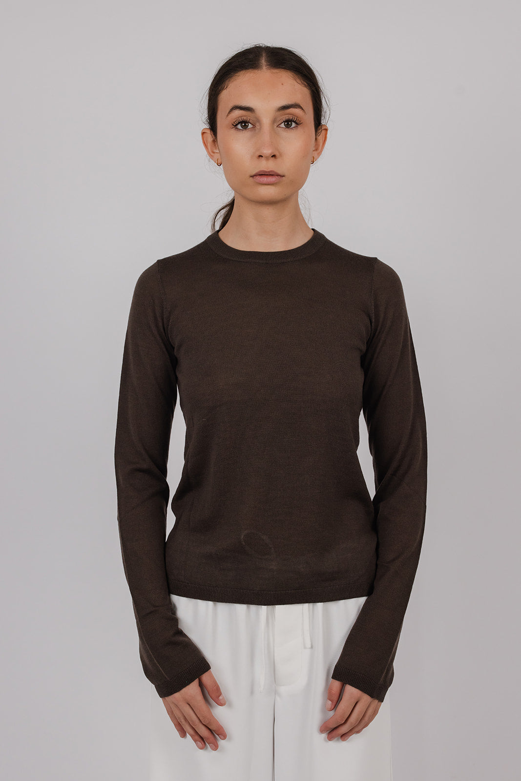 Model wearing a chocolate coloured long-sleeve merino top and white pants by Vic and Bert.